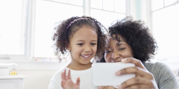 Cheerful daughter and mother having video chat on phone